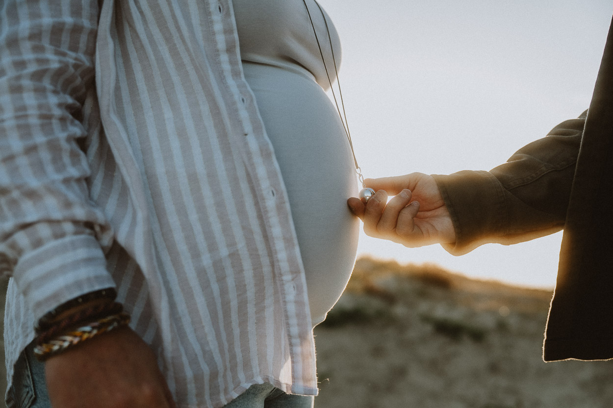 Tendre moment en Landes : future maman touchée, amour partagé dans une lumière douce à Dax, capturé avec authenticité.
