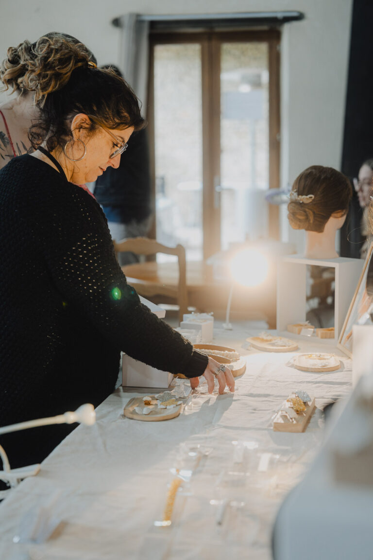 Une femme élégante observe des bijoux sous une douce lumière, ambiance chaleureuse signée photographe famille Landes.
