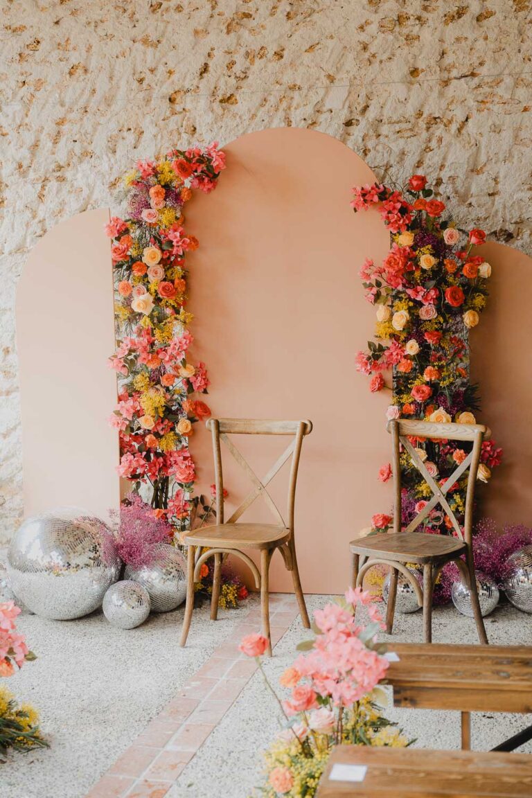 Imaginez deux chaises bois devant un décor pêche et fleuri, ambiance douce et élégante pour photos de famille dans les Landes.