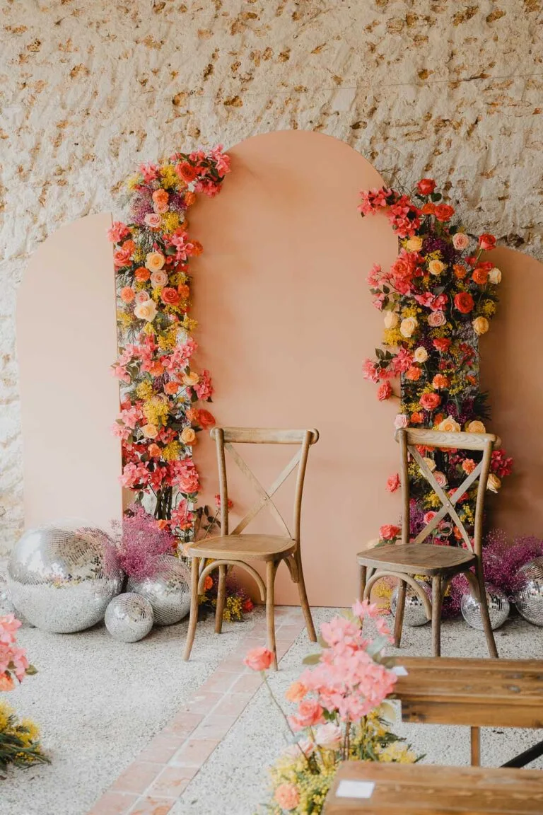 Imaginez deux chaises bois devant un décor pêche et fleuri, ambiance douce et élégante pour photos de famille dans les Landes.