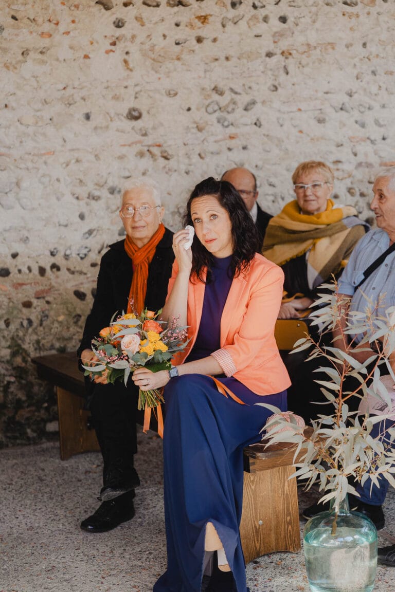 Instant d'émotion capturé : une femme, bouquet en main, émue, entourée de proches dans une salle chaleureuse des Landes.