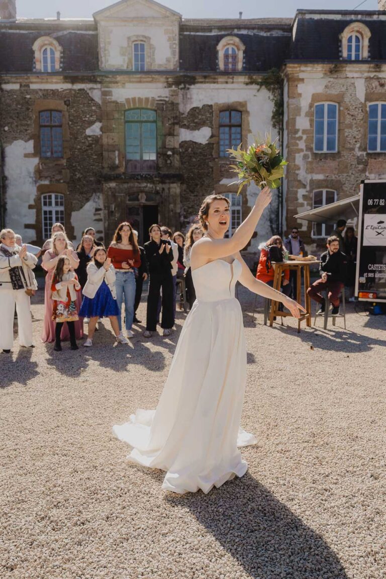 Une mariée radieuse s'apprête à lancer son bouquet devant ses proches, sous le soleil des Landes, ambiance joyeuse et sincère.
