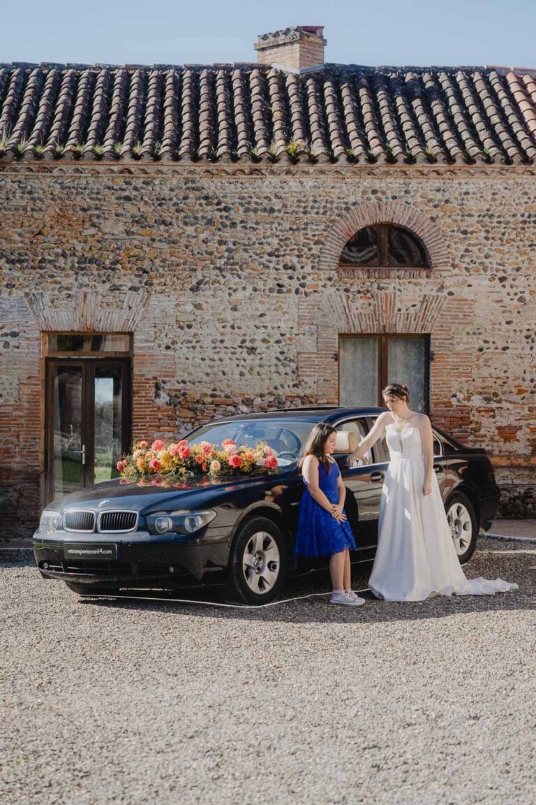 Instant tendre devant une bâtisse en pierre, la mariée et une fillette créent un souvenir unique dans les Landes.