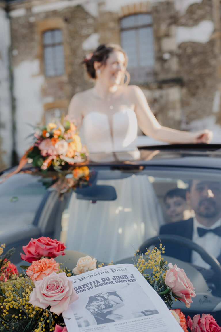 Une mariée radieuse en robe blanche dans une décapotable fleurie, bouquet à la main, scène douce capturée dans les Landes.