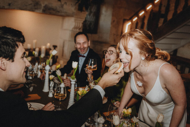 Instant de tendresse à table : une femme en robe blanche croque un biscuit, entourée de sourires doux, ambiance familiale Landes.