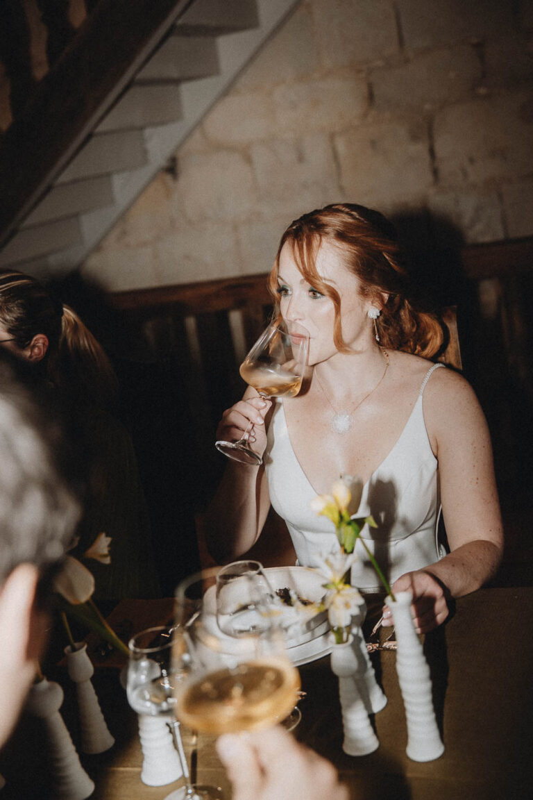 Douce ambiance de mariage dans les Landes : une femme élégante partage un moment chaleureux parmi fleurs, rires et convives.