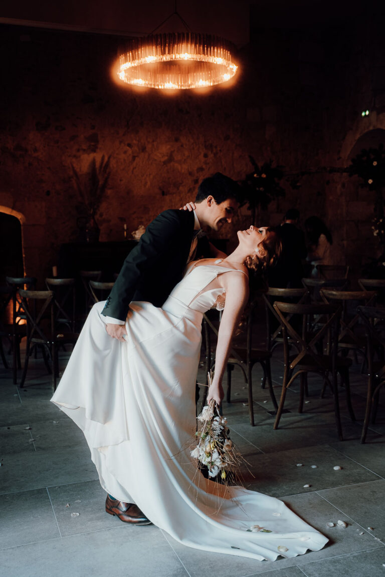 Un couple de mariés échange un tendre baiser sous une belle lumière, pétales au sol, ambiance intime des Landes.