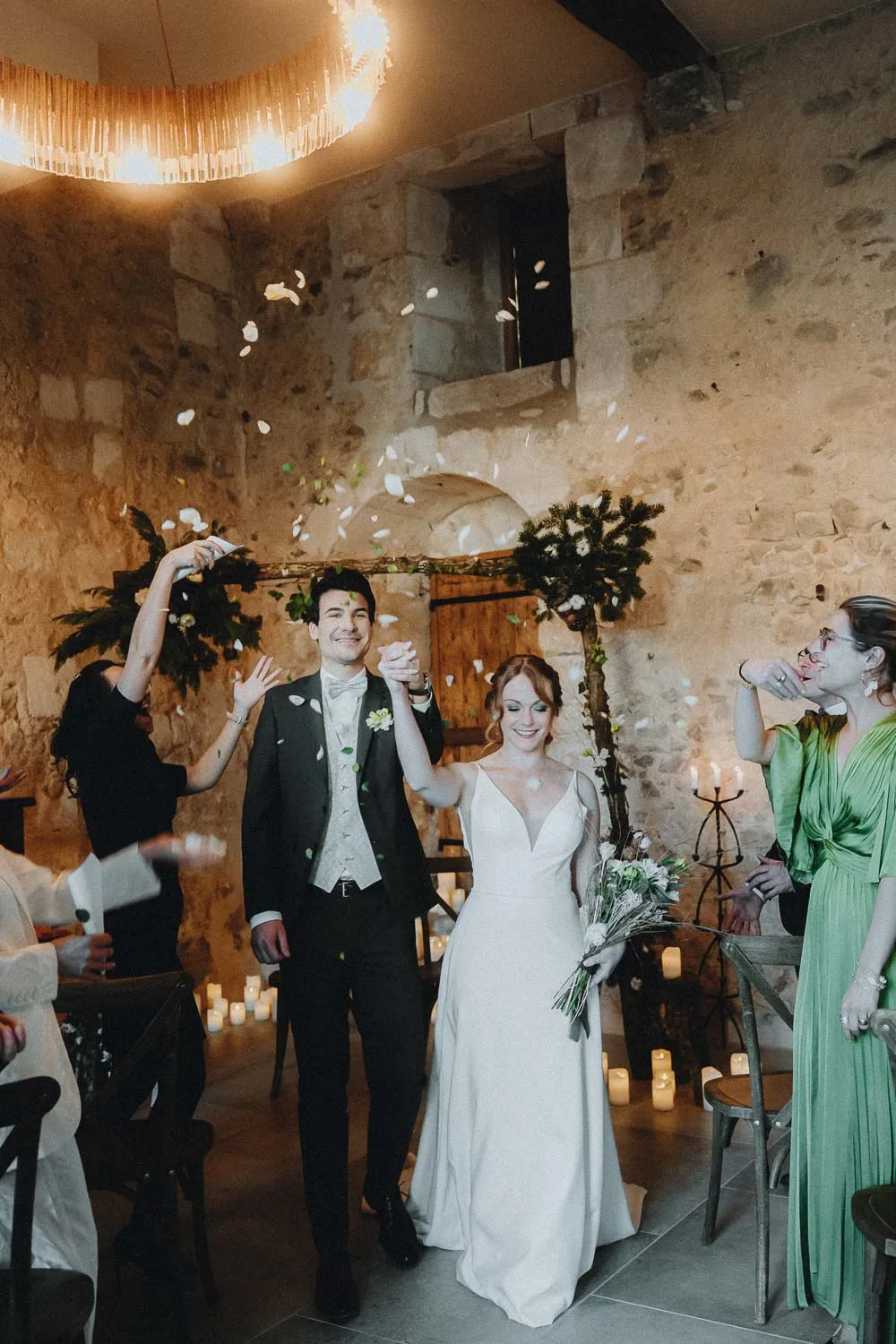 Un couple s'avance main dans la main, entouré de pétales, ambiance chaleureuse et authentique immortalisée dans les Landes.