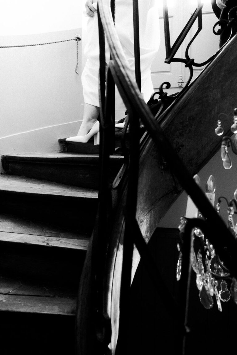 Moment tendre : une élégante descend l'escalier, lumière douce, ambiance raffinée, signé photographe famille Landes.