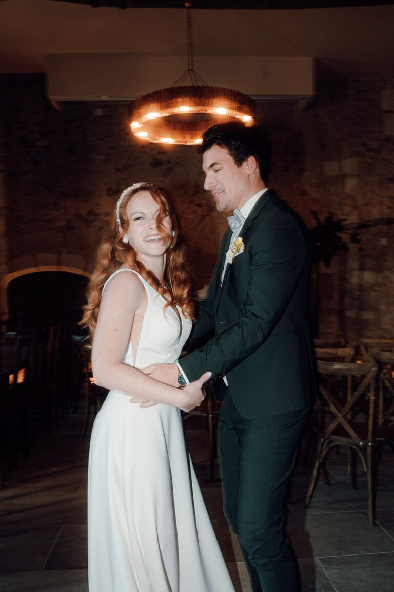 Un joli couple danse main dans la main sous un lustre moderne, sourire complice, capturés avec douceur dans une ambiance landaise.