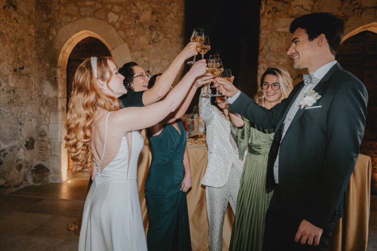 Dans une belle salle en pierres, mariés et proches trinquent, capturés avec douceur par un photographe de mariage dans les Landes.