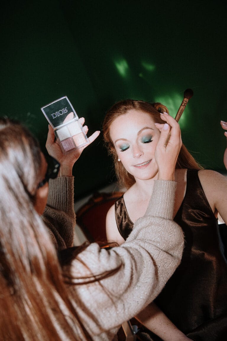 Doux moment beauté, la maquilleuse sublime un regard vert sous la lumière délicate d'une séance photo mariage dans les Landes.