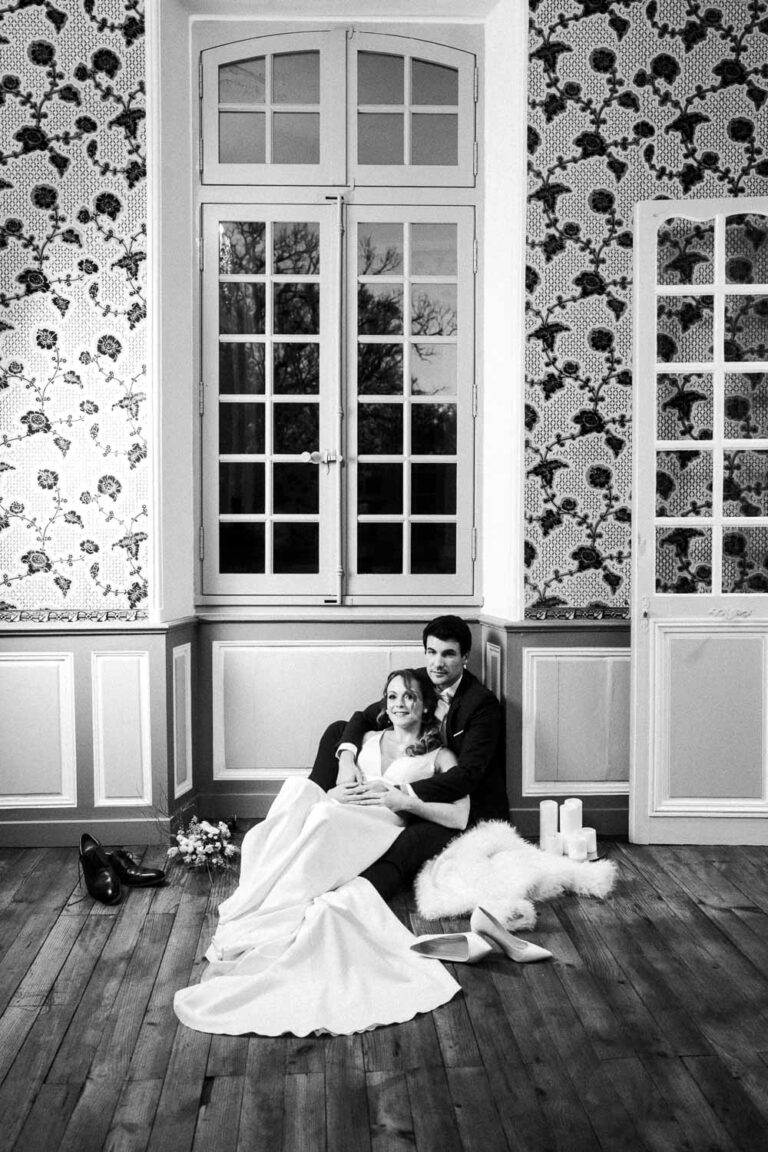 Moment intime d'un couple assis près de la fenêtre, bouquet et bougies, lumière douce, ambiance Landes mariage authentique.