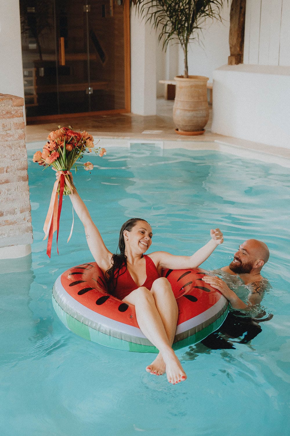 Joie d'un couple en séance famille à la piscine près de Dax, rire sur bouée pastèque sous le soleil des Landes.