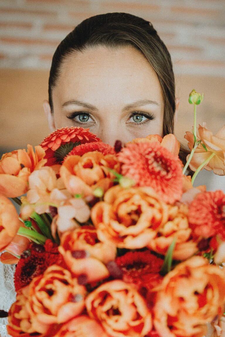 Regard pétillant derrière un grand bouquet orangé, instant famille capturé à Dax par Allison Micallef, photographe Landes.