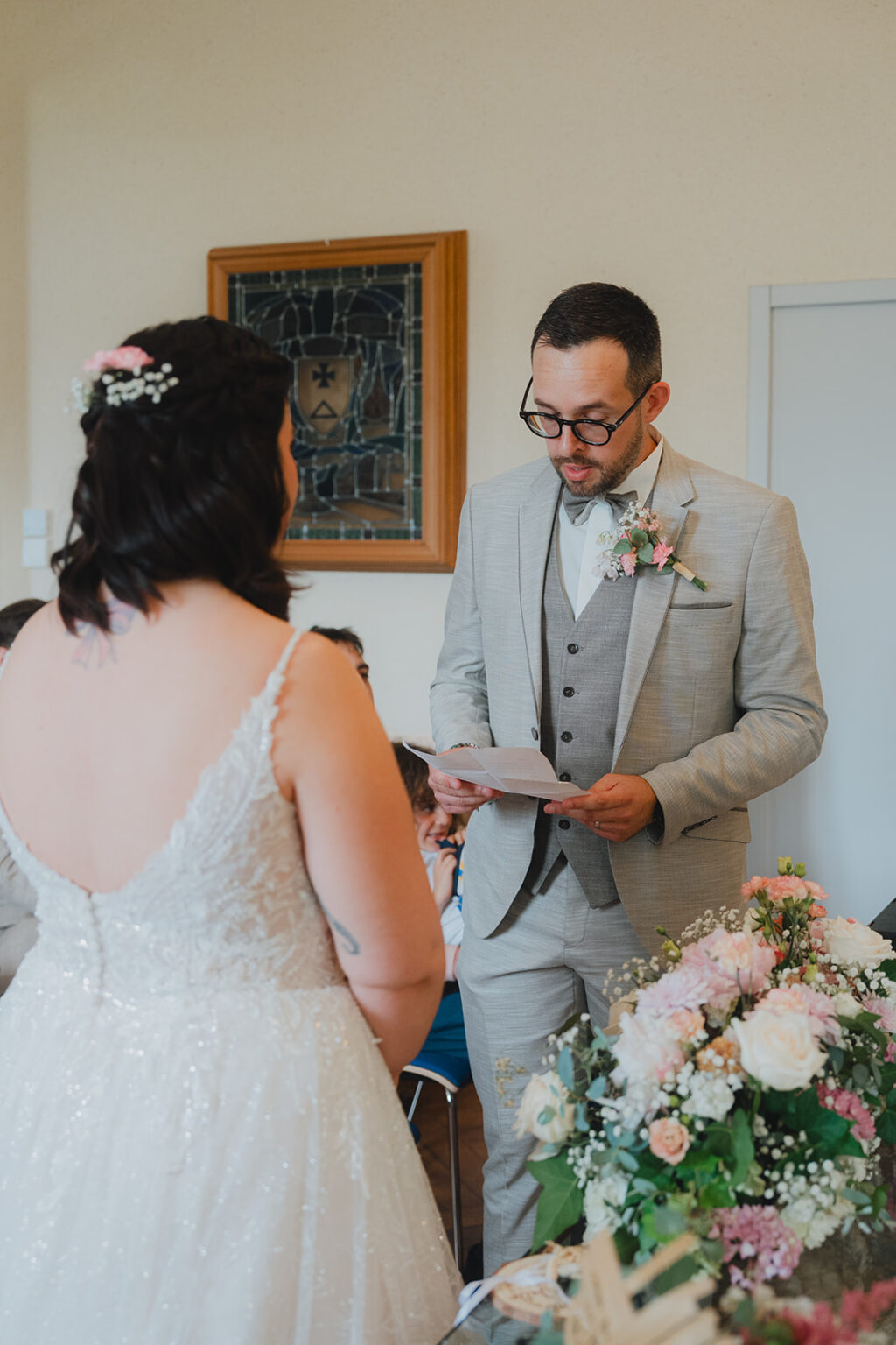 Un moment de complicité lors d’une cérémonie de mariage à Dax : échange de vœux et émotion partagée, dans un décor floral raffiné.