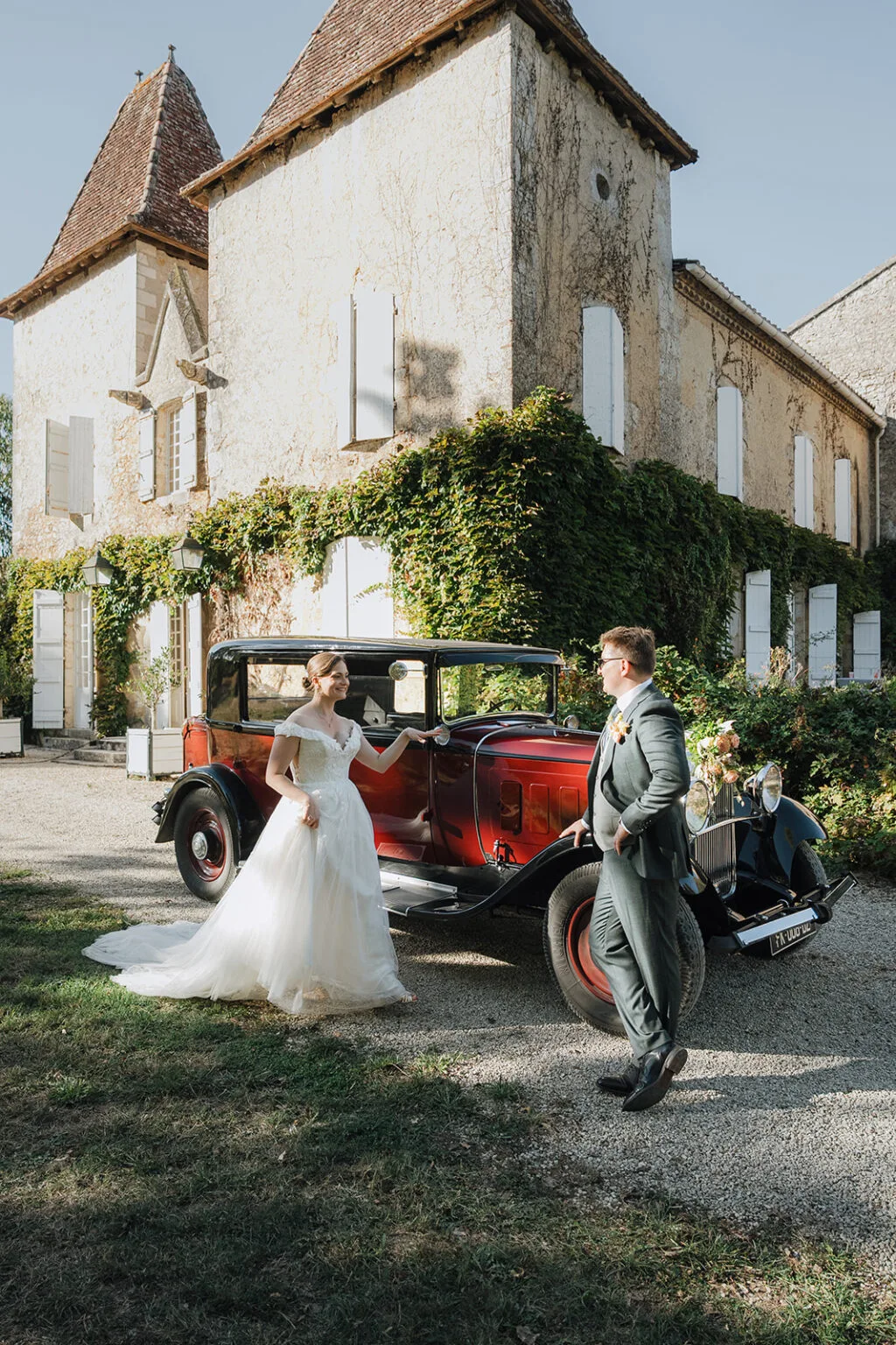Des jeunes mariés complices devant une voiture ancienne et un château à Dax, dans les Landes.