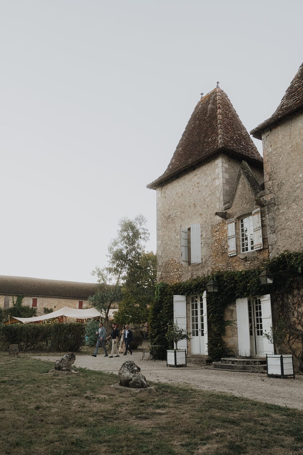 Des invités traversant le jardin d'un domaine en pierre pour se rendre à un mariage dans les Landes.