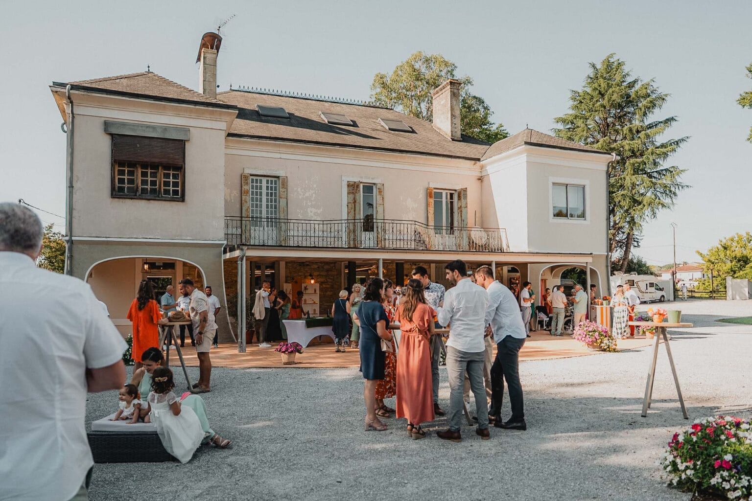 Des convives partageant un moment de joie dans le jardin d’un domaine en pierre, dans les Landes.