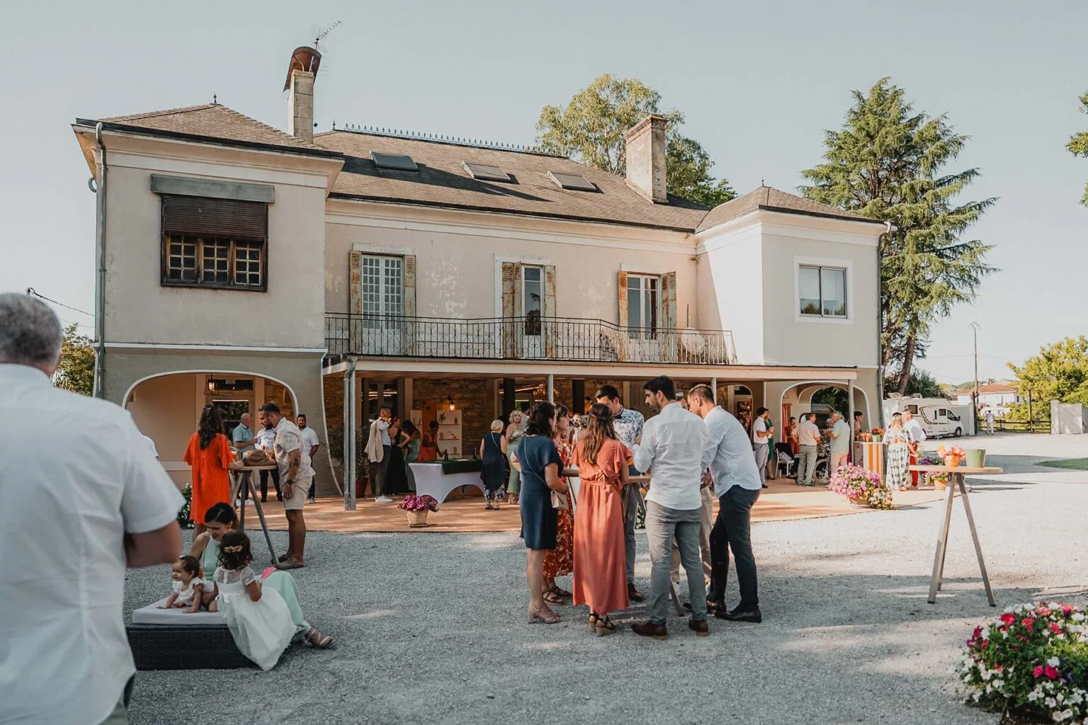 Des convives partageant un moment de joie dans le jardin d’un domaine en pierre, dans les Landes.