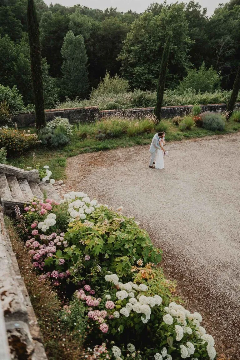 Jeunes mariés s’embrassant dans un domaine fleuri des Landes. Photographe de mariage à Dax.