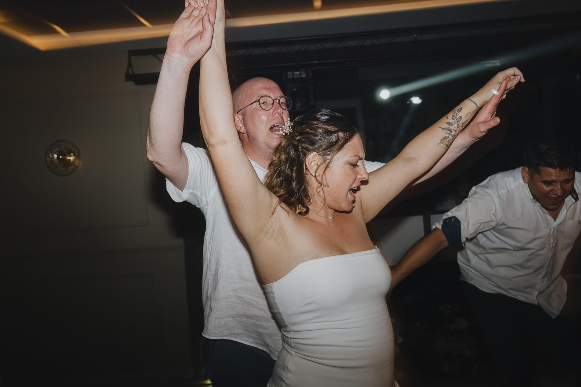 Une mariée les bras levés sur la piste de danse