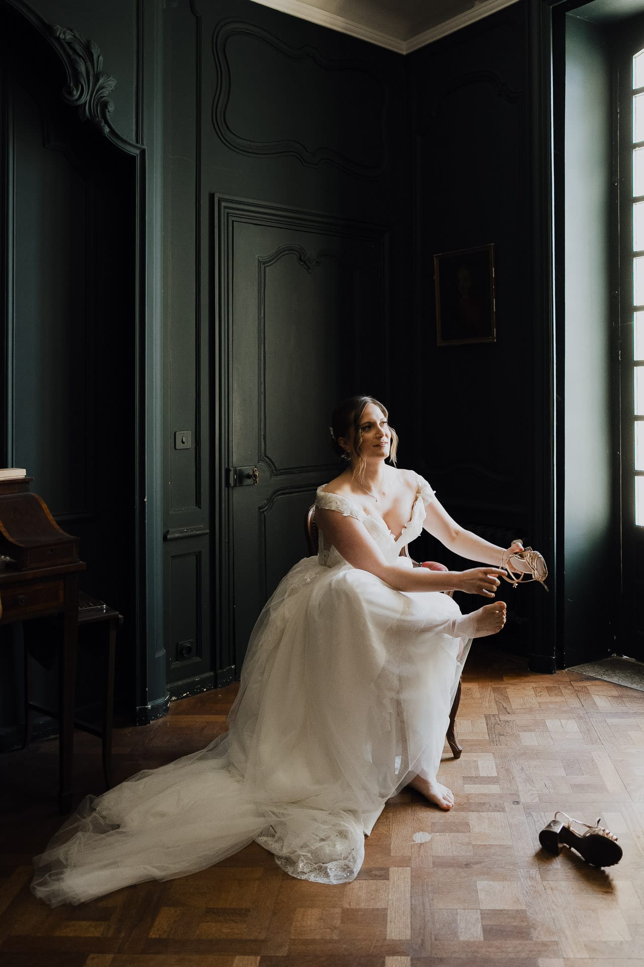 La mariée seule près d’une fenêtre, dans la lumière des préparatifs
