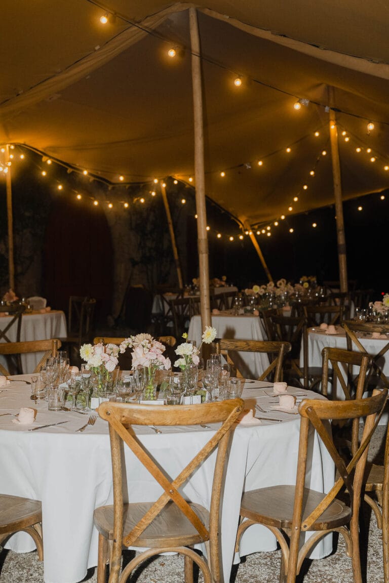 Des tables de réception décorées de fleurs sous un chapiteau illuminé pour un mariage à Dax, dans les Landes.