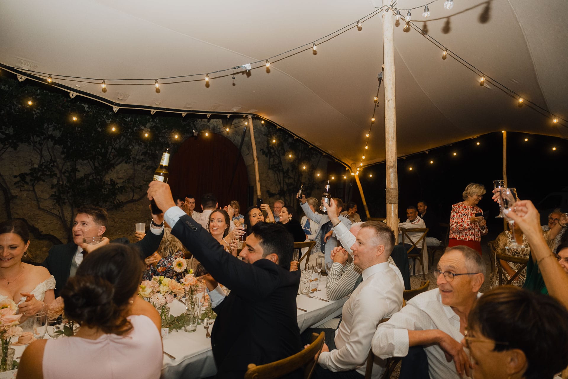 Le toast des invités sous les guirlandes lumineuses