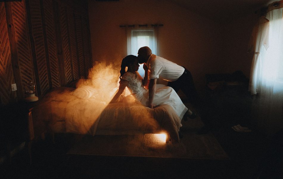 Mariés blottis sur un lit, complicité et tendresse dans une lumière douce, photo de mariage à Dax dans les Landes.