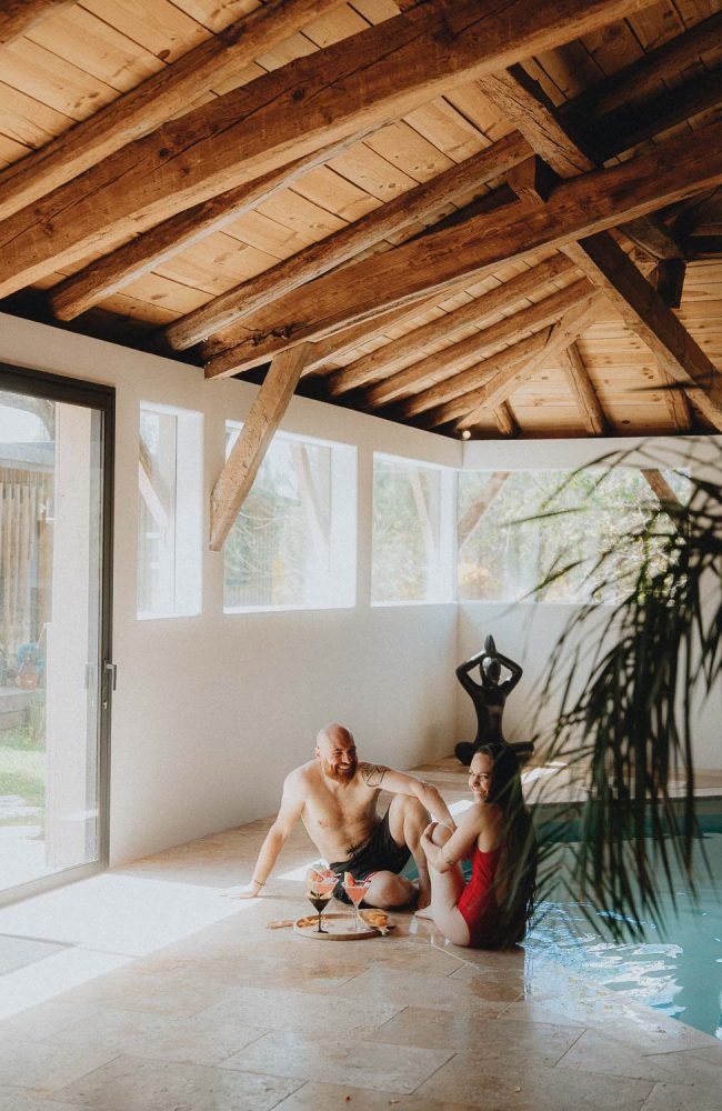 Moment complice d'un couple près d'une piscine intérieure à Dax, lumière douce et ambiance cosy en séance famille Landes.