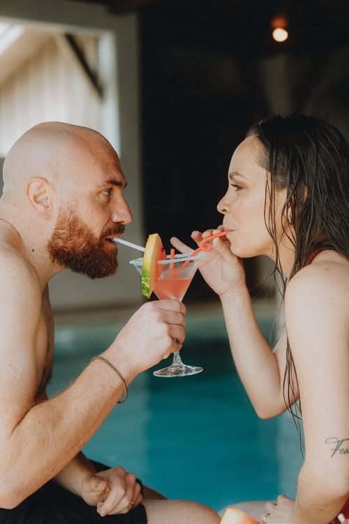 Couple complice partageant un cocktail au bord d'une piscine à Dax, séance photo famille en été dans les Landes.