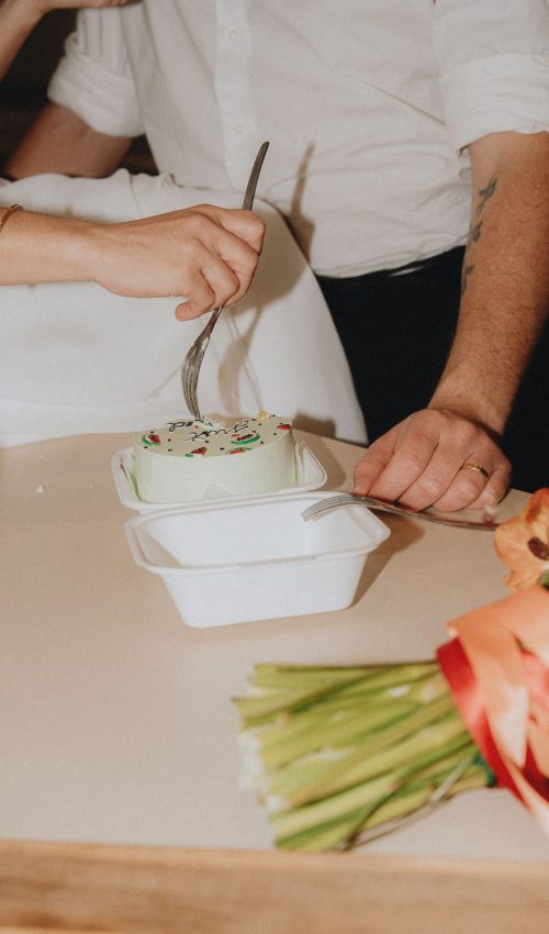 Moment complice lors d'une séance famille à Dax : couple coupant un gâteau fleuri, ambiance douce et joyeuse.
