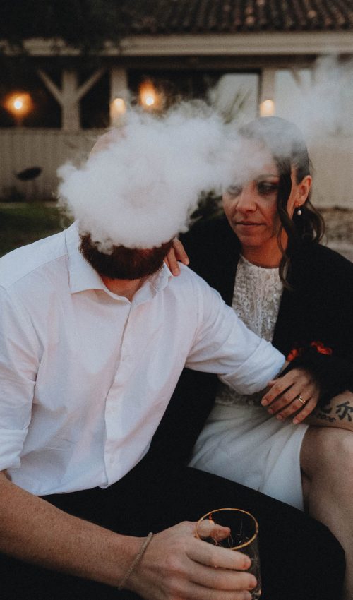 Deux personnes rient en extérieur à Dax, un nuage de fumée flotte, instant complice d'une séance photo famille Landes.