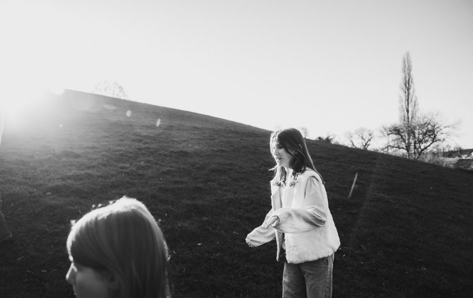 Sourires d'enfants sur une colline ensoleillée à Dax, séance photo en famille dans les Landes avec vue sur les arbres et le ciel bleu.