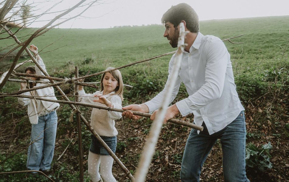 Les sourires d'un papa et de ses enfants en train de construire une cabane en bois en pleine nature à Dax, séance photo en famille dans les Landes.