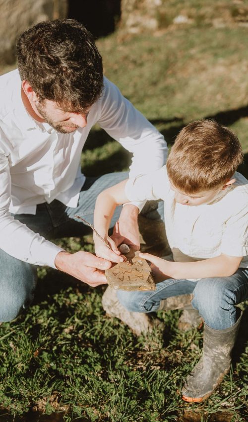 Complicité entre un parent et son enfant alors qu’ils assemblent un puzzle en bois sur l’herbe, séance photo en famille à Dax, dans les Landes.