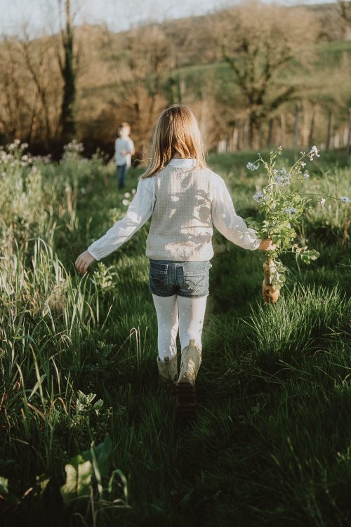 Des enfants explorant une prairie ensoleillée des Landes, rires et tendresse lors d’une séance photo en famille à Dax, dans les Landes.