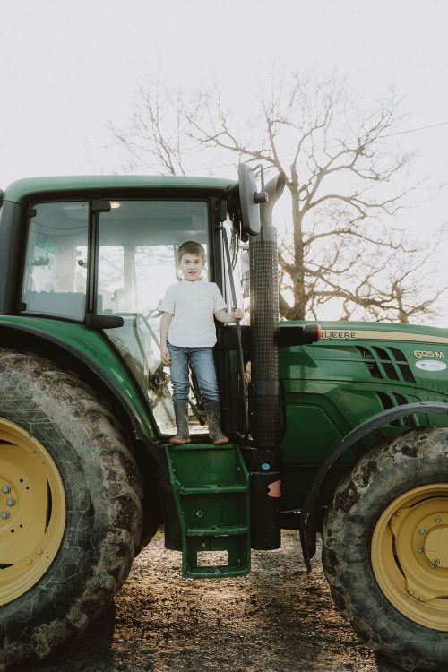 Un enfant souriant monte sur un tracteur vert, la porte ouverte : un moment de complicité immortalisé à Dax par Allison Micallef.