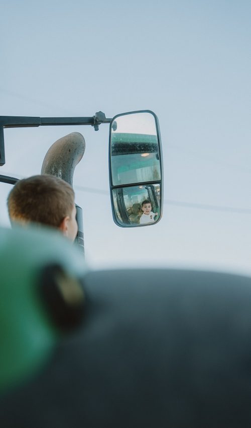 Le sourire d’un enfant capturé dans le rétroviseur d’un camion, sous un ciel bleu à Dax, lors d’une séance photo en famille pleine de spontanéité.