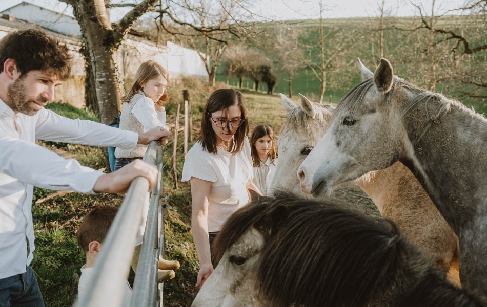 Une famille rayonnante à Dax partageant un moment de complicité avec des chevaux sous le soleil des Landes, séance photo naturelle.