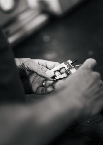 Dans cette image en noir et blanc inspirant la tranquillité des vacances dans les Landes, un photographe de mariage et de famille capture une scène où une personne mesure méticuleusement un petit objet avec des pieds à coulisse, évoquant la précision sereine similaire aux moments paisibles passés en bord de mer, symbole d'un art attentif et soigné typique des photographes professionnels spécialisés dans les mariages et portraits familiaux dans cette région emblématique.