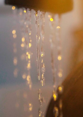 Un moment de douceur : l'eau s'écoule en fins filets sous une lumière chaude, ambiance intime comme à Hossegor.